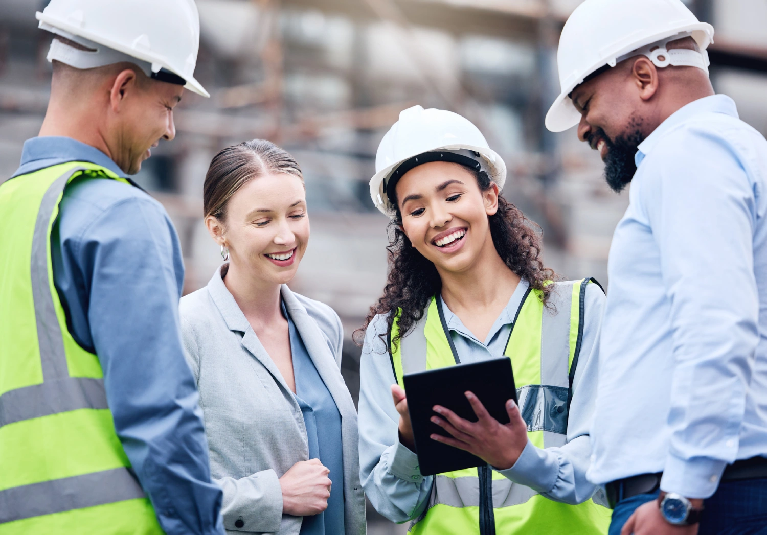 A group of people in hard hats and vests looking at something on a tablet.